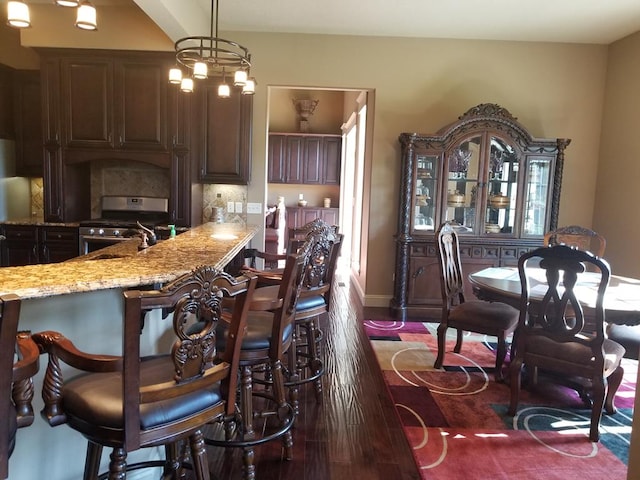 kitchen with gas stove, dark brown cabinets, dark hardwood / wood-style floors, and decorative light fixtures