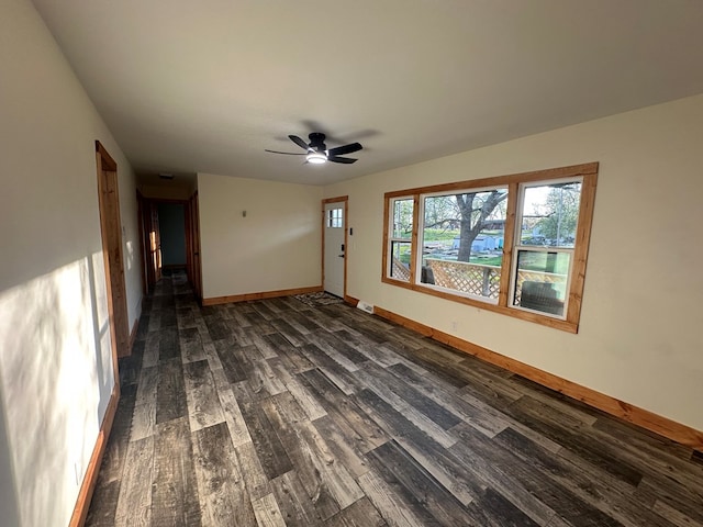 empty room featuring ceiling fan, baseboards, and dark wood-style flooring