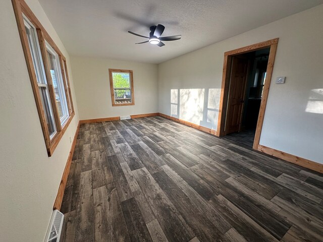 spare room with visible vents, baseboards, dark wood-style floors, and ceiling fan