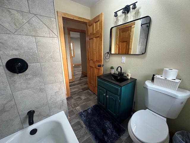 bathroom with a tub to relax in, stone finish floor, vanity, and toilet