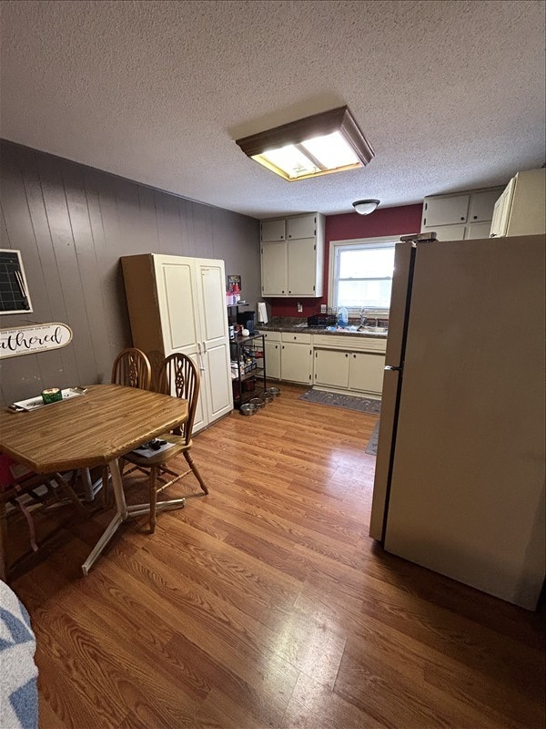 116 Adams St, Centralia, MO 65240 - kitchen with freestanding refrigerator, dark wood-style floors, a textured ceiling, dark countertops, and a sink