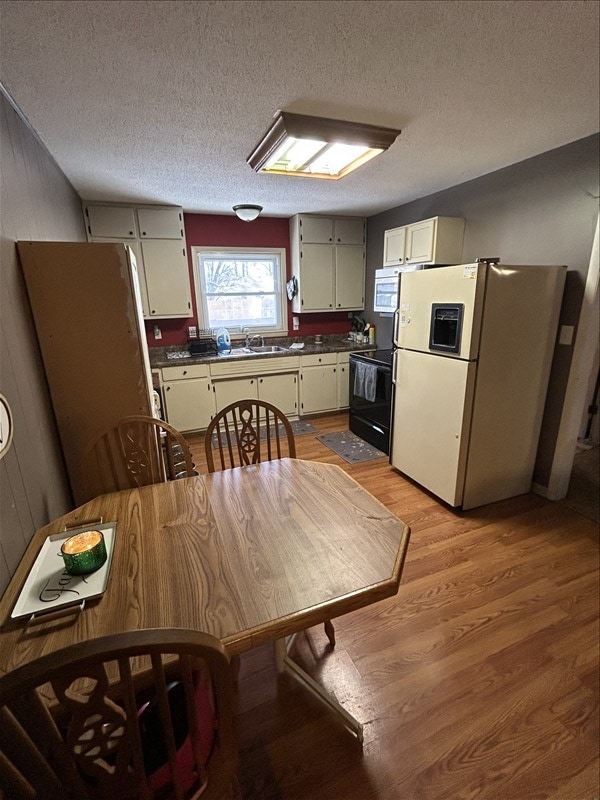116 Adams St, Centralia, MO 65240 - kitchen featuring freestanding refrigerator, black range with electric stovetop, light wood-type flooring, a sink, and dark countertops