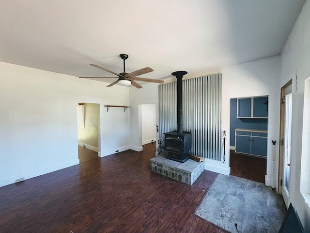 living room with ceiling fan, a wood stove, and dark hardwood / wood-style floors