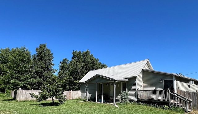 rear view of property featuring a wooden deck and a yard