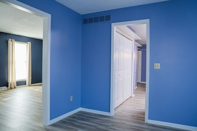 hallway with wood-type flooring and a textured ceiling