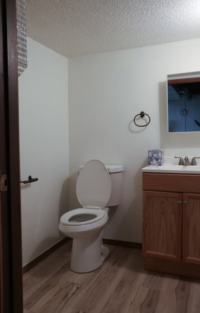 bathroom featuring hardwood / wood-style floors, vanity, a textured ceiling, and toilet