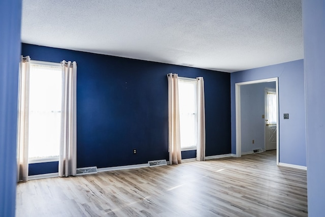 unfurnished room featuring light hardwood / wood-style floors and plenty of natural light