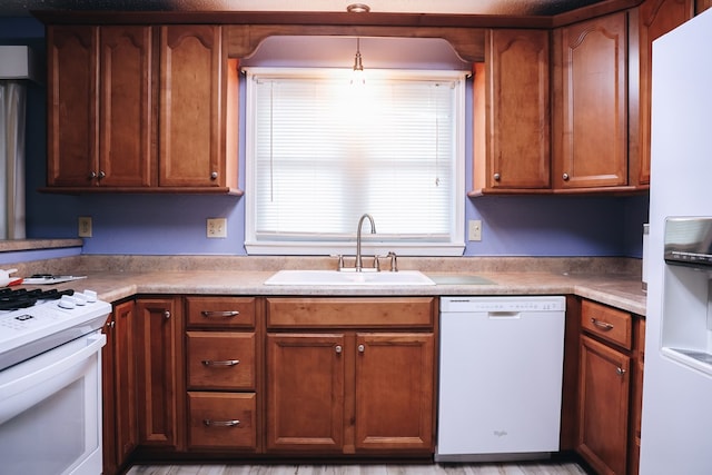 kitchen featuring white appliances, hanging light fixtures, and sink