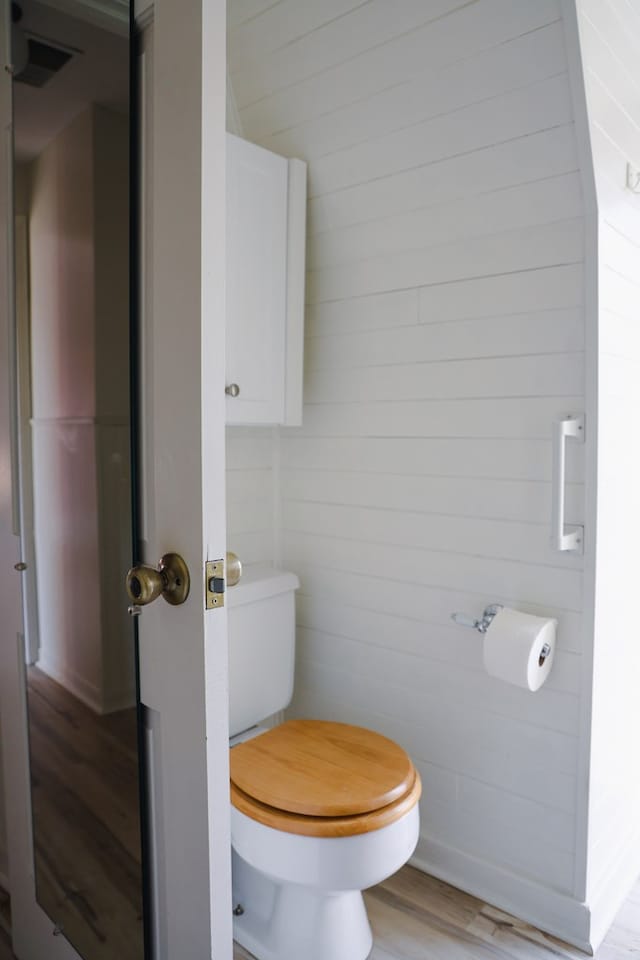 bathroom with wooden walls, wood-type flooring, and toilet