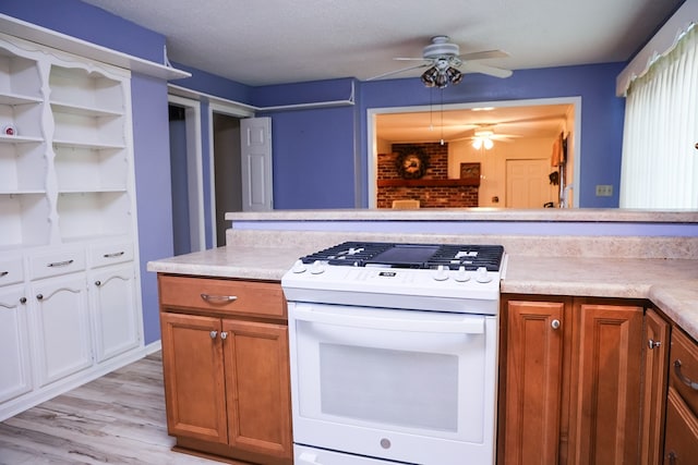 kitchen with light wood-type flooring, a textured ceiling, electric range, and ceiling fan