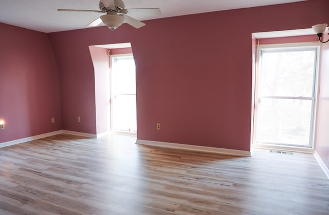 spare room with light hardwood / wood-style floors, a wealth of natural light, and ceiling fan