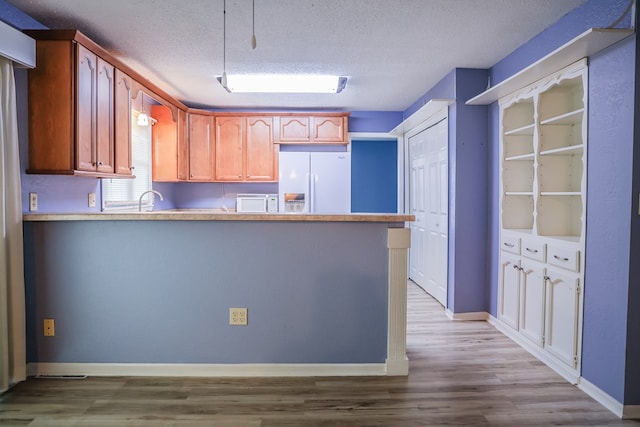 kitchen featuring kitchen peninsula, a textured ceiling, light hardwood / wood-style floors, and white fridge with ice dispenser