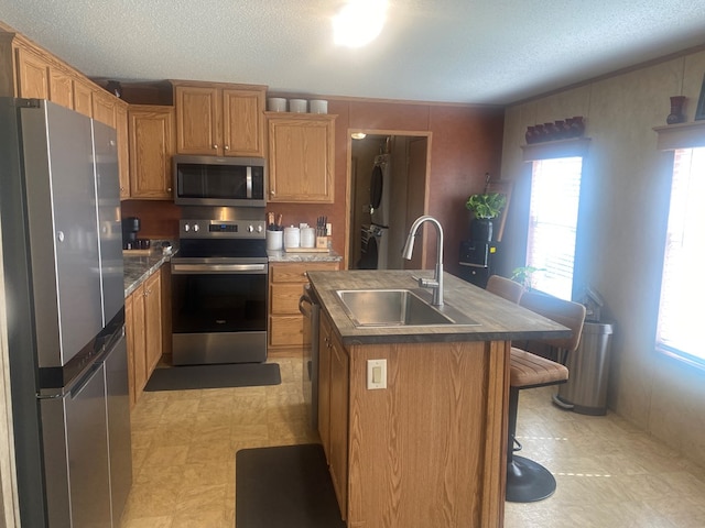 302 Mead St, Utica, MO 64686 - kitchen with a sink, stainless steel appliances, a textured ceiling, stacked washer / drying machine, and an island with sink