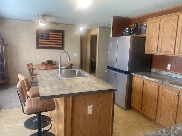 302 Mead St, Utica, MO 64686 - kitchen featuring a sink, freestanding refrigerator, a breakfast bar area, an island with sink, and a ceiling fan