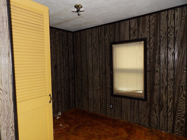 unfurnished room with wood walls and a textured ceiling