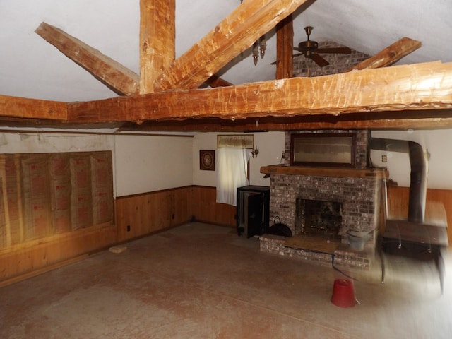 unfurnished living room featuring vaulted ceiling with beams, a brick fireplace, ceiling fan, and wooden walls