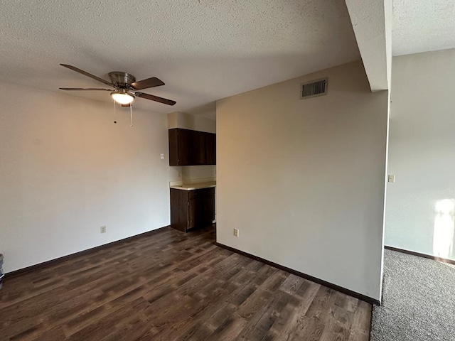 unfurnished room with dark hardwood / wood-style flooring, a textured ceiling, and ceiling fan