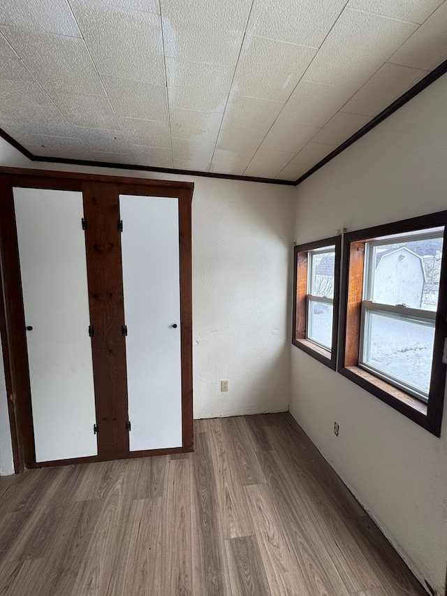 unfurnished room with ornamental molding and wood-type flooring