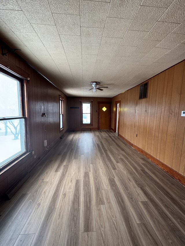 unfurnished room with ceiling fan, wooden walls, and hardwood / wood-style flooring