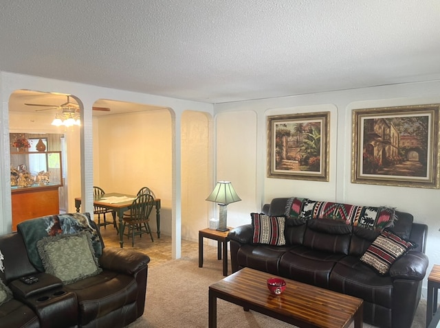 carpeted living room with ceiling fan and a textured ceiling