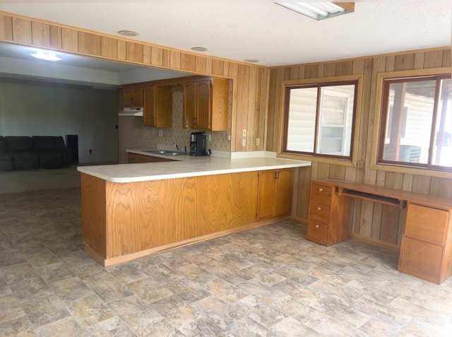 kitchen featuring kitchen peninsula, wooden walls, and sink