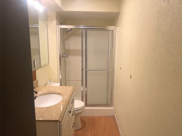 bathroom with vanity, hardwood / wood-style flooring, toilet, and walk in shower