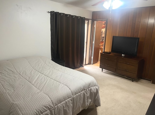 carpeted bedroom featuring ceiling fan and wooden walls