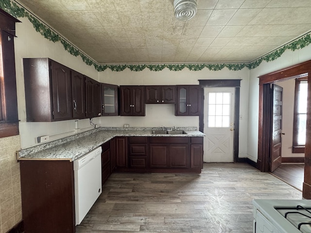 kitchen featuring dishwasher, sink, hardwood / wood-style flooring, light stone counters, and dark brown cabinets