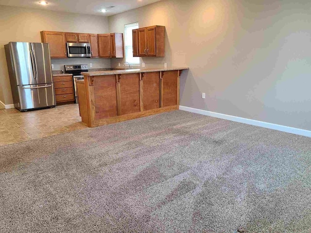 601/603 W Laharpe St, Kirksville, MO 63501 - kitchen with baseboards, appliances with stainless steel finishes, a peninsula, brown cabinetry, and light carpet