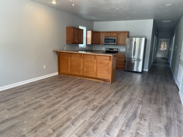 601/603 W Laharpe St, Kirksville, MO 63501 - kitchen with baseboards, a peninsula, brown cabinetry, stainless steel appliances, and a sink