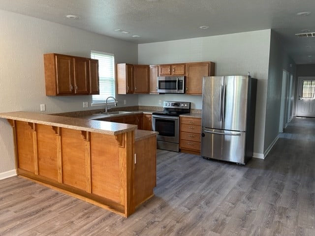 601/603 W Laharpe St, Kirksville, MO 63501 - kitchen featuring visible vents, a sink, appliances with stainless steel finishes, a peninsula, and brown cabinets