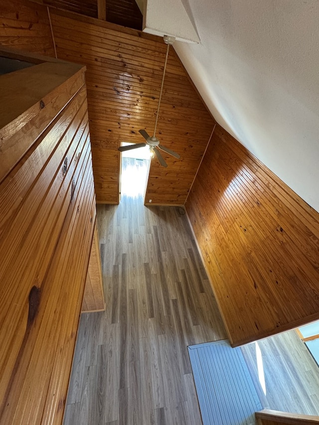 additional living space with wood-type flooring, wooden walls, and vaulted ceiling