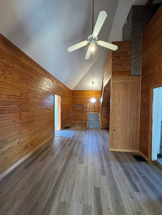 bonus room with high vaulted ceiling, dark wood-type flooring, wood walls, and ceiling fan