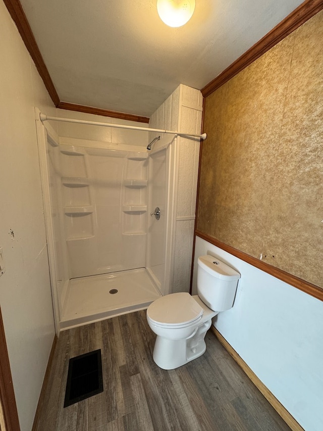 bathroom featuring a shower, hardwood / wood-style floors, toilet, and crown molding