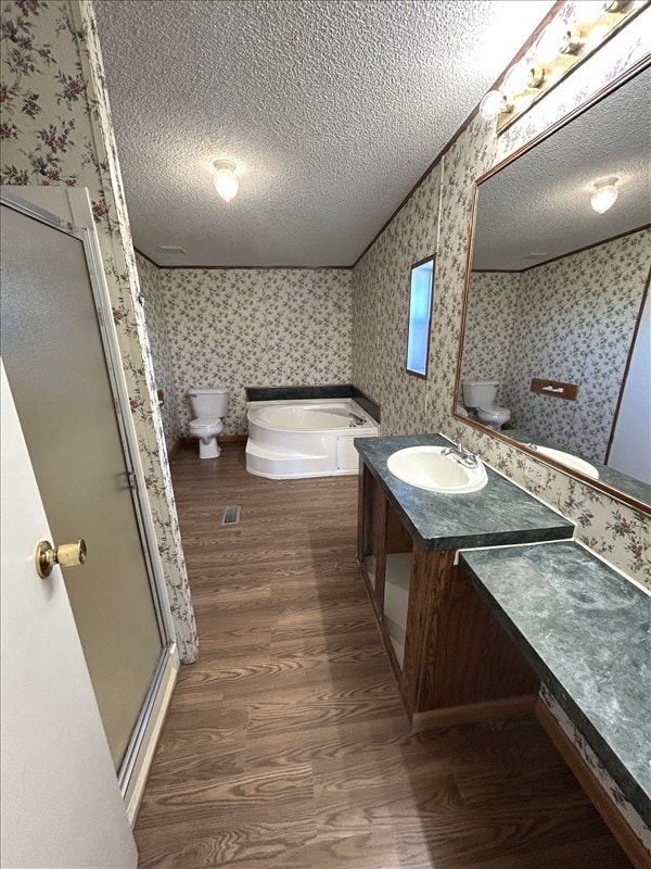 full bathroom with separate shower and tub, wood-type flooring, a textured ceiling, and toilet