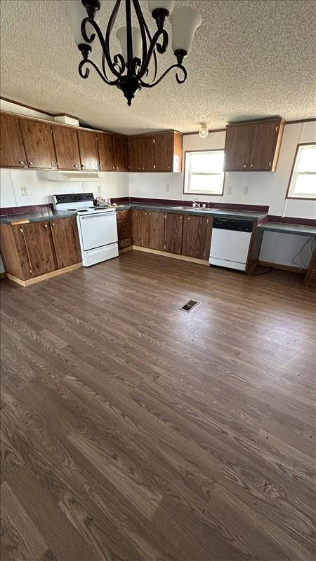 kitchen with decorative light fixtures, dark hardwood / wood-style floors, white appliances, and an inviting chandelier