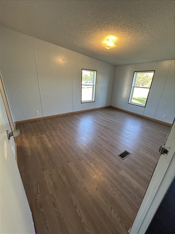 spare room with a textured ceiling and dark hardwood / wood-style floors