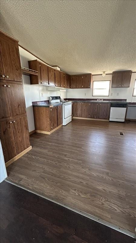 kitchen featuring a textured ceiling, white appliances, and dark hardwood / wood-style floors