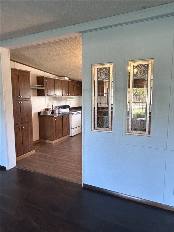 kitchen with a textured ceiling, white range with electric stovetop, dark wood-type flooring, and vaulted ceiling