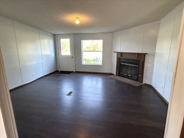 unfurnished living room with a textured ceiling and dark hardwood / wood-style floors