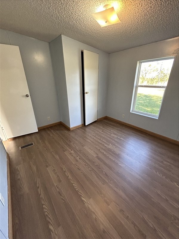 spare room with a textured ceiling and dark hardwood / wood-style floors