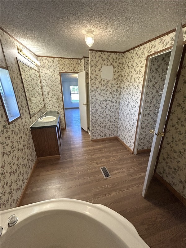 bathroom with a bathing tub, vanity, wood-type flooring, and a textured ceiling