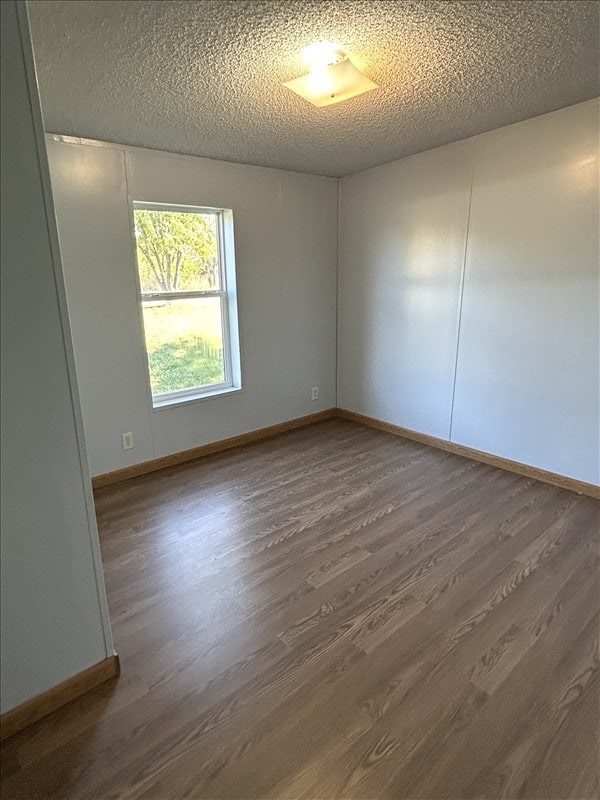 unfurnished room featuring dark hardwood / wood-style flooring and a textured ceiling