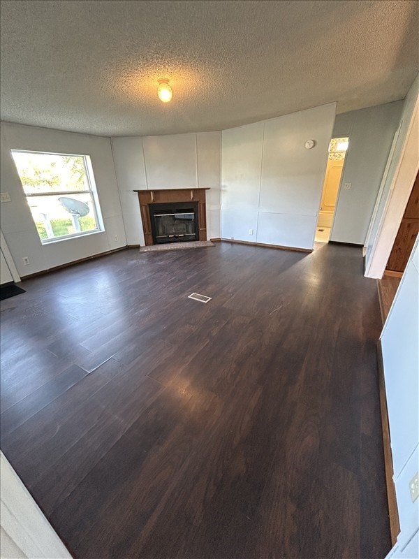 unfurnished living room featuring a textured ceiling and dark hardwood / wood-style floors