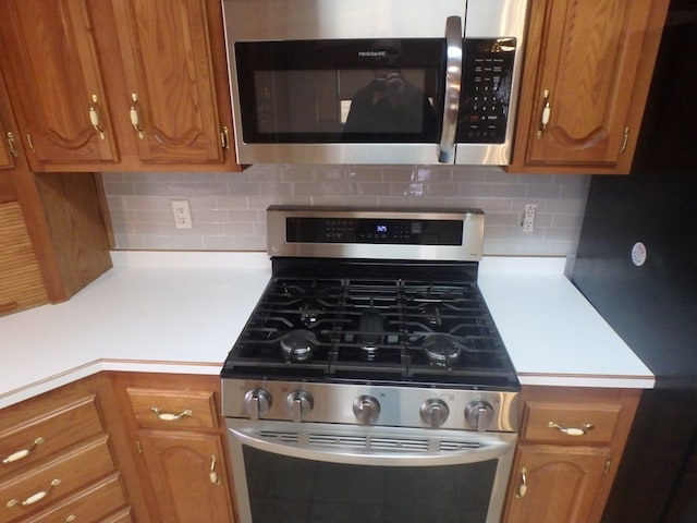 kitchen with light countertops, appliances with stainless steel finishes, brown cabinetry, and tasteful backsplash