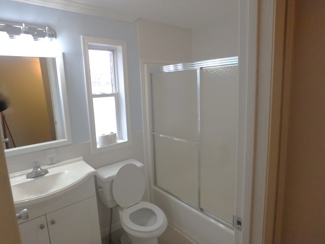 full bathroom featuring toilet, combined bath / shower with glass door, and vanity