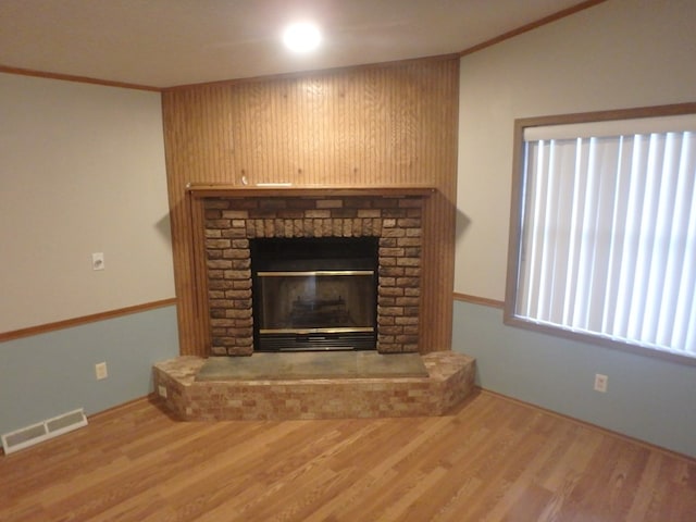 details featuring crown molding, visible vents, wood finished floors, and a glass covered fireplace