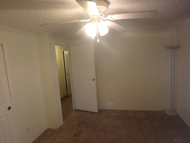 empty room featuring a textured ceiling, ornamental molding, carpet flooring, and a ceiling fan