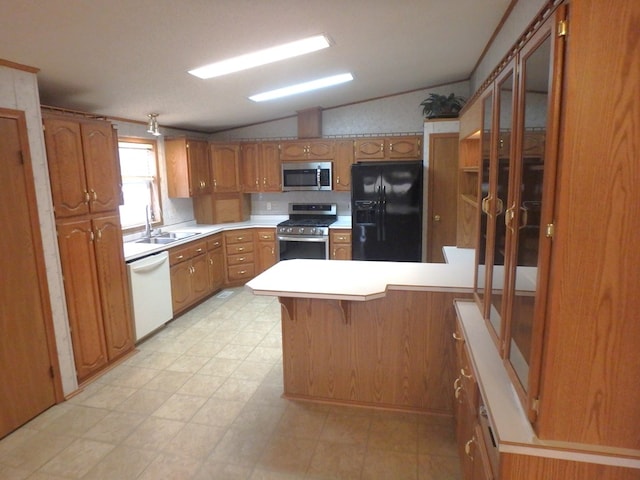 kitchen featuring lofted ceiling, appliances with stainless steel finishes, a peninsula, light countertops, and a sink