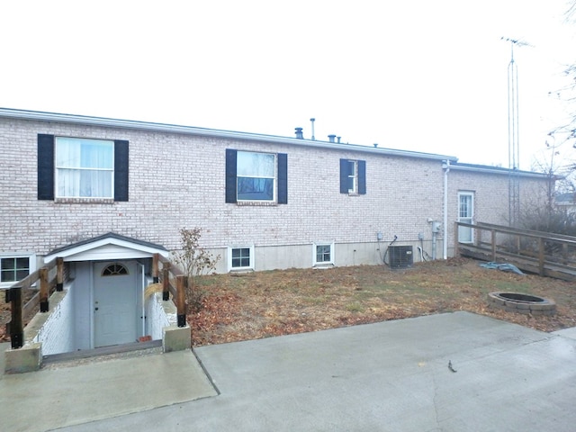 back of house featuring cooling unit, brick siding, and a patio